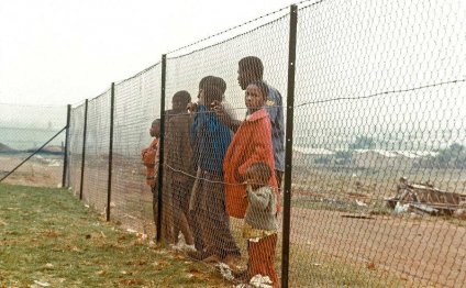 Children stand behind a fence
